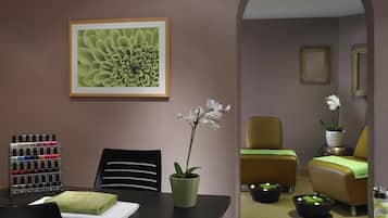 A room with a dining table, chairs, a potted orchid, a framed artwork, and a sofa.