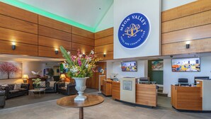 A hotel lobby with a reception desk, seating area, and a large floral centerpiece. - Meon Valley Hotel, Spa & Golf (Southampton)