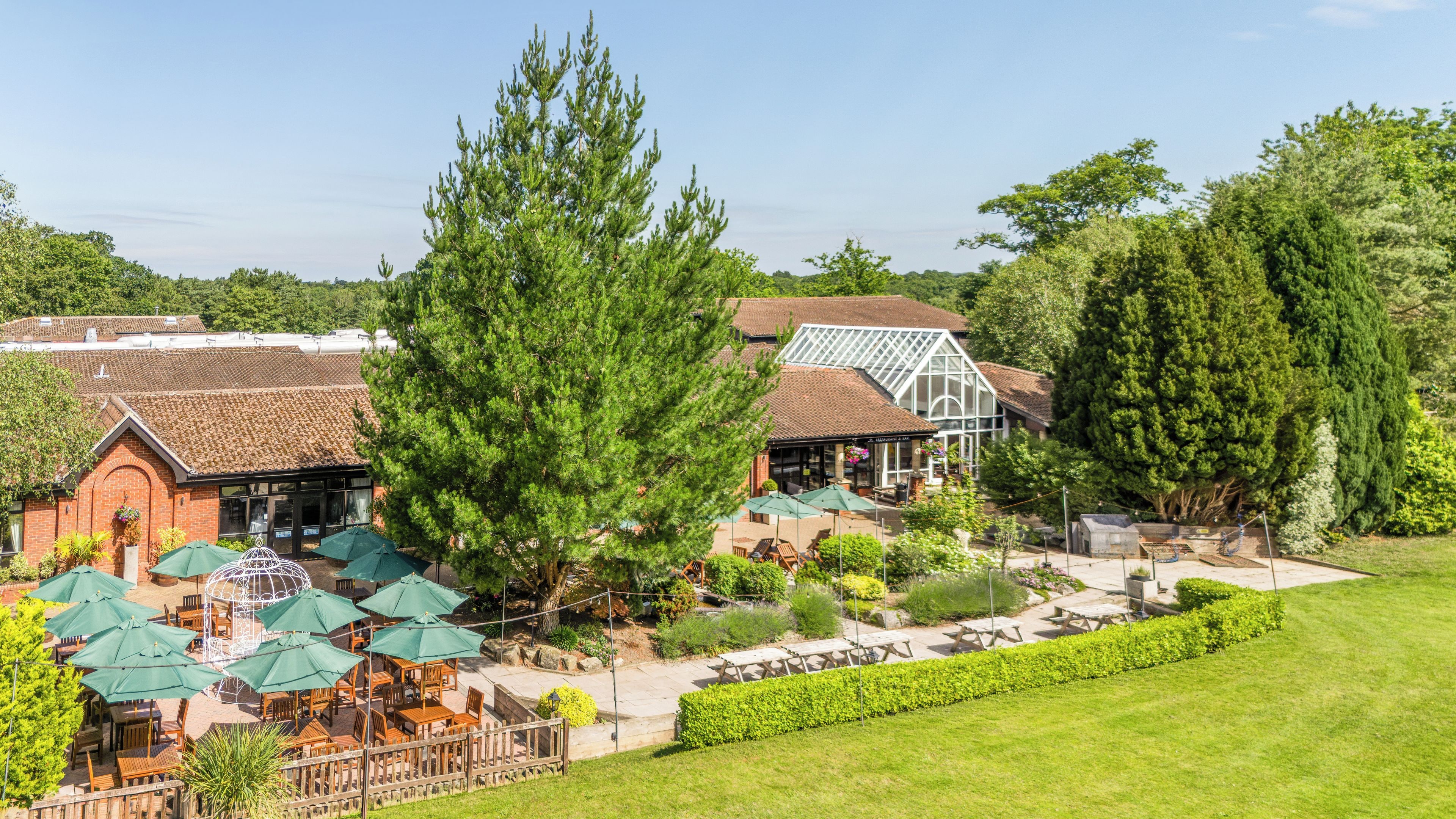 A hotel with outdoor seating, a greenhouse, and a well-maintained garden.