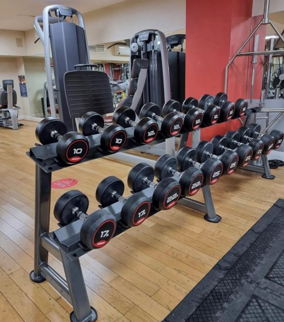 A gym with a rack of dumbbells and weight machines.