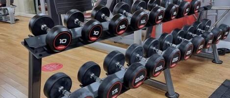 A gym with a rack of dumbbells and weight machines.