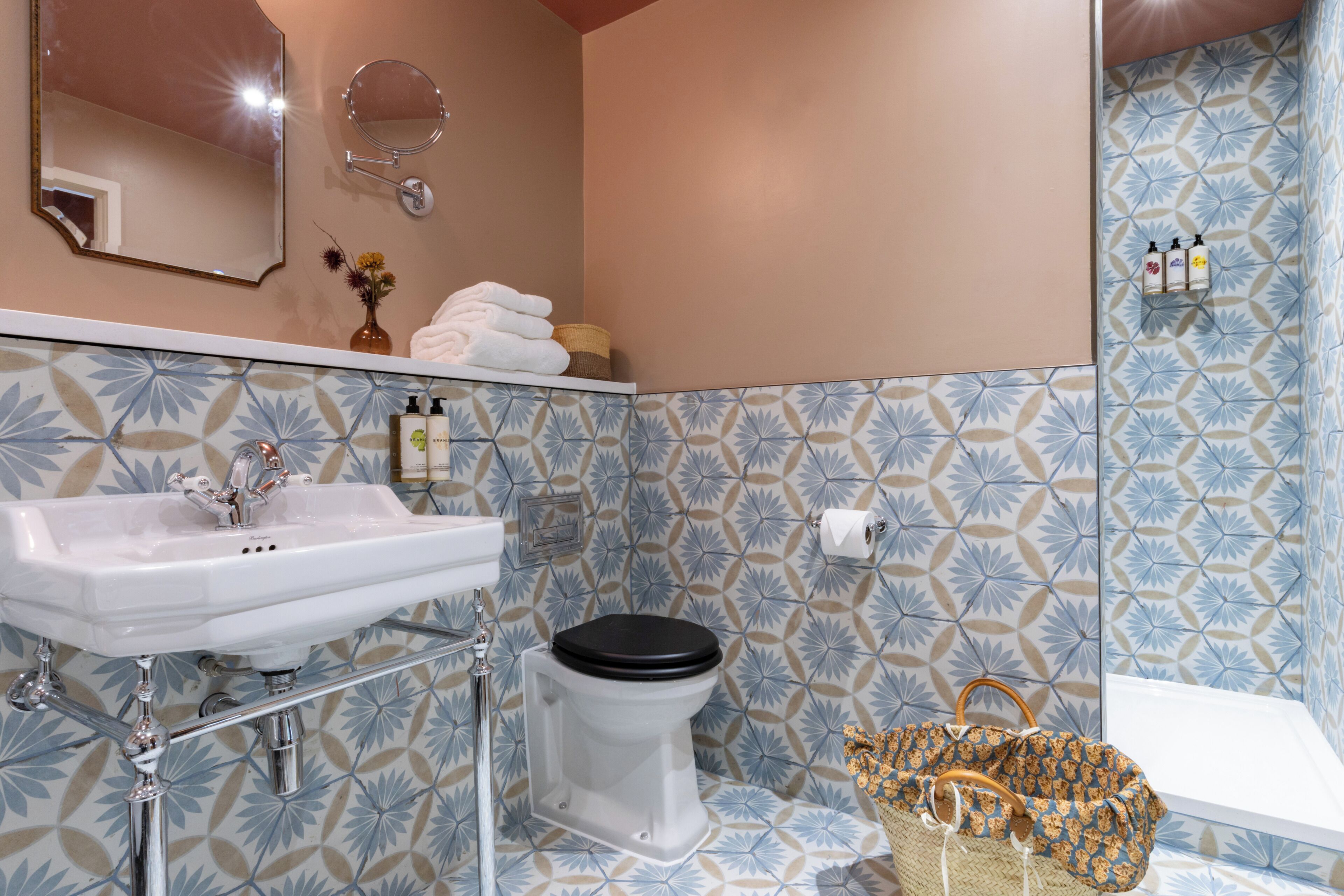 A bathroom with a white sink, a toilet, a mirror, and a shower area.