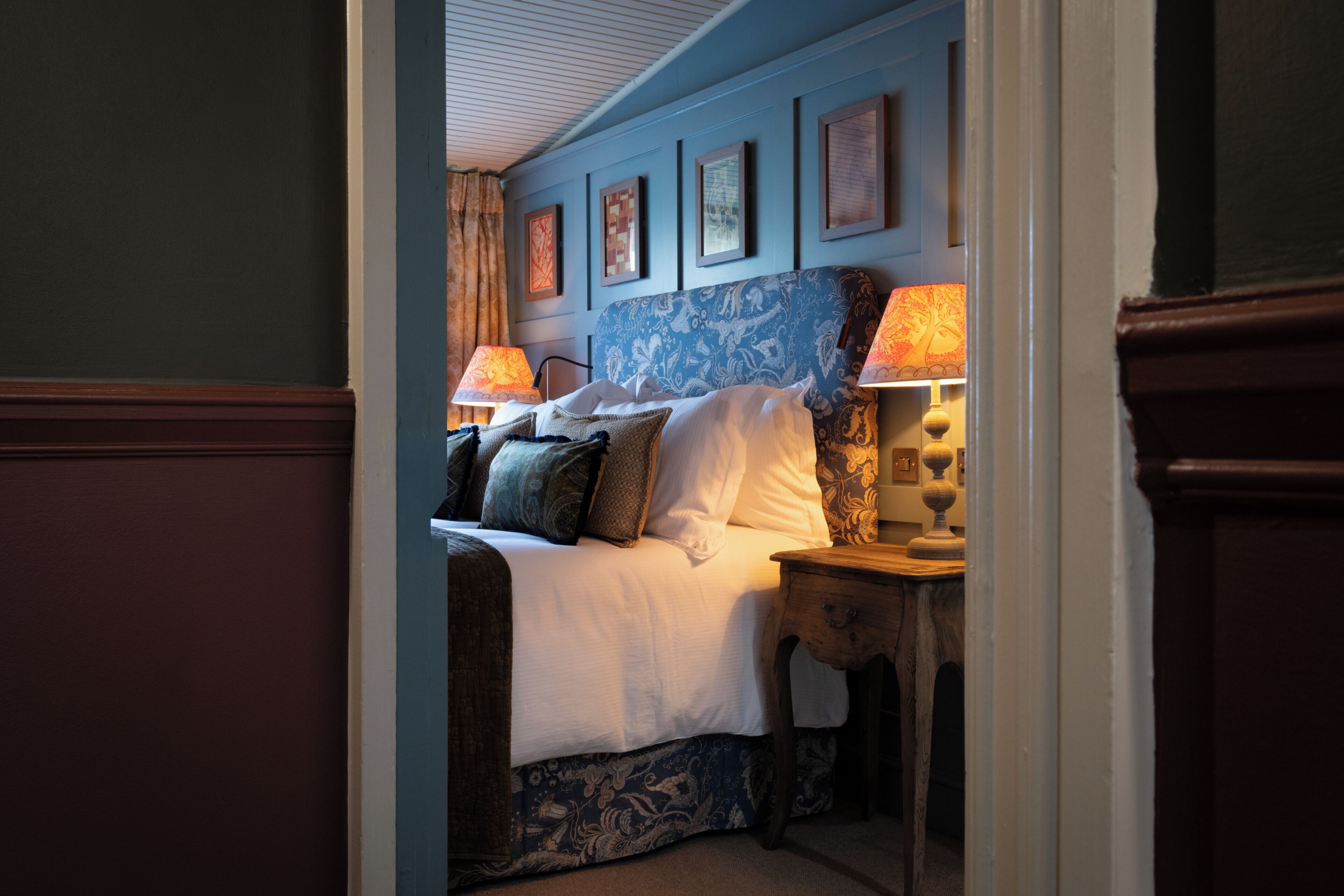 Une chambre à coucher avec un lit, deux tables de chevet et un mur orné de tableaux encadrés.