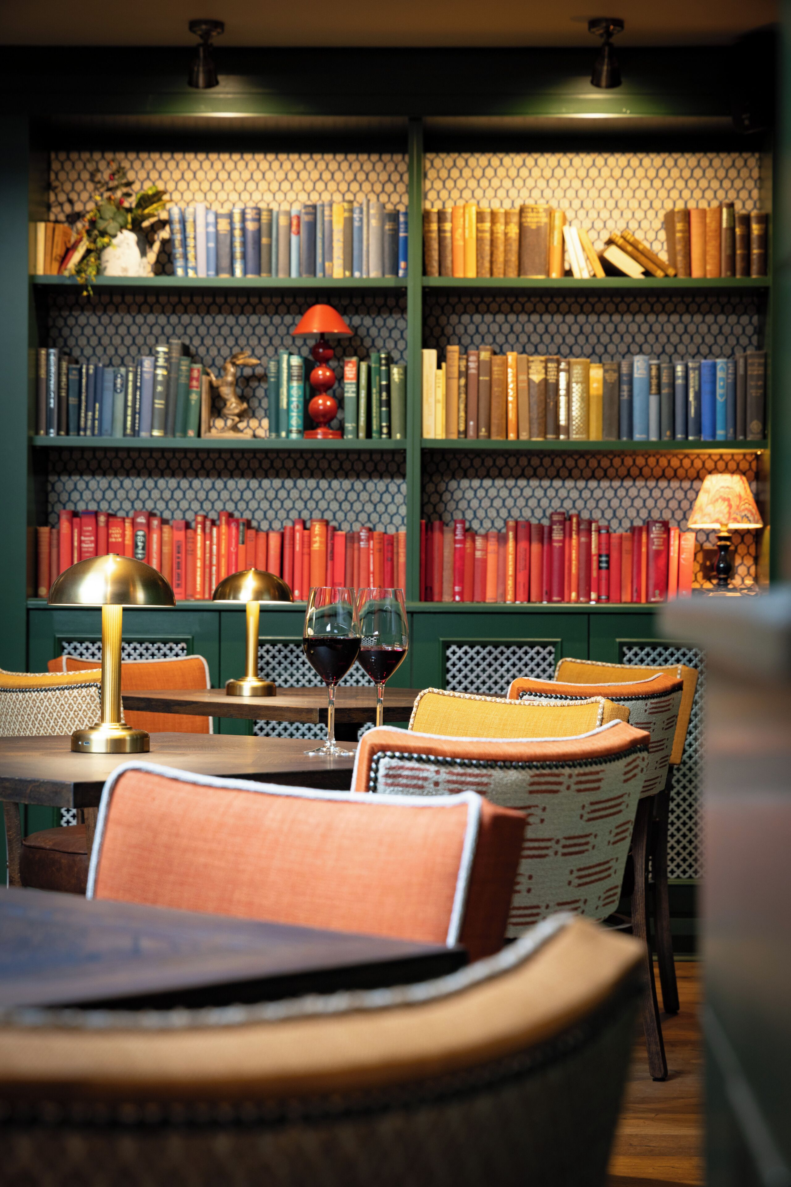 Una biblioteca con estanterías, una mesa con sillas y una lámpara.