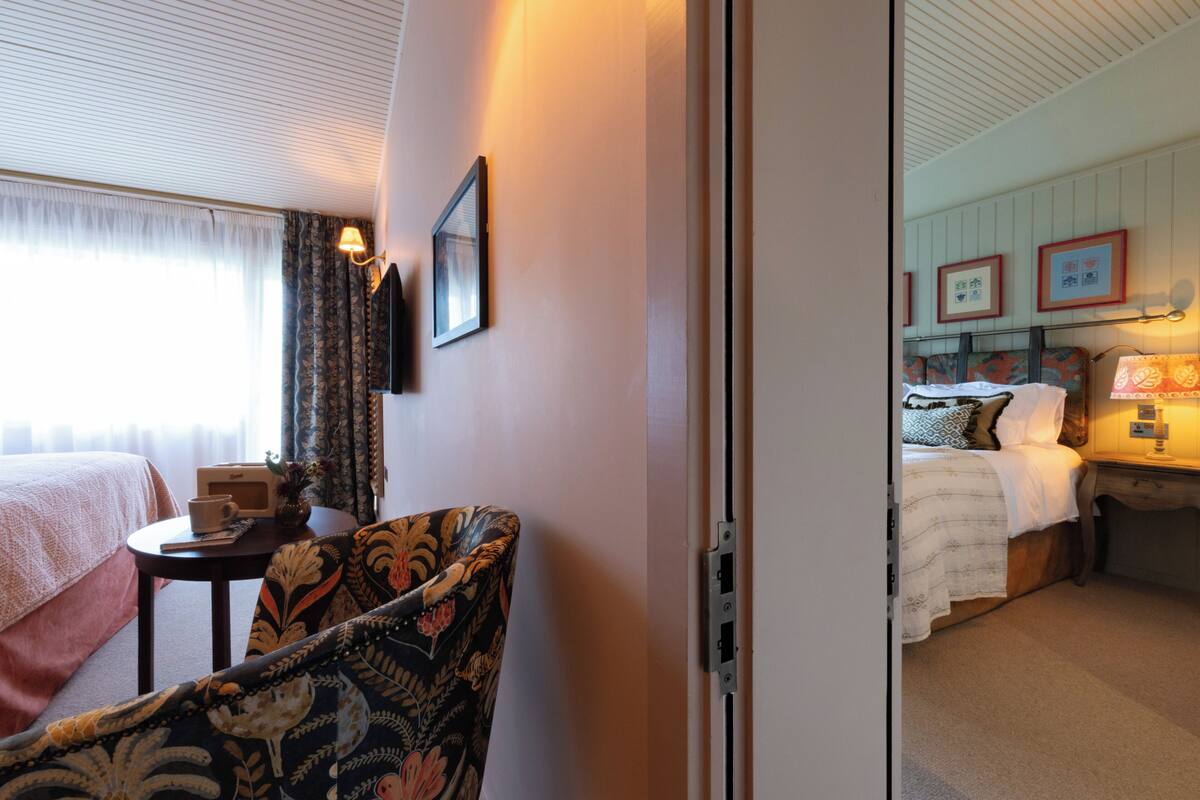 Een hotelkamer met een bed, een stoel, een klein tafeltje en een nachtkastje.