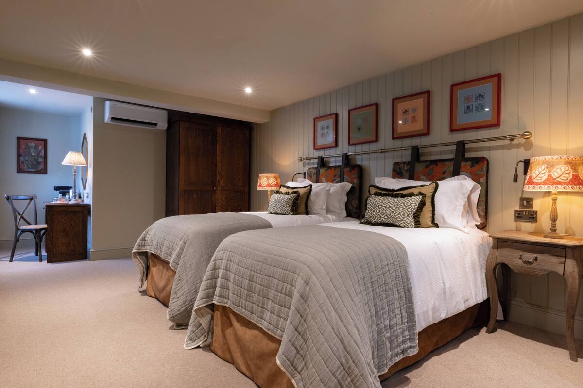Een slaapkamer met twee bedden, een bureau en een airconditioning.