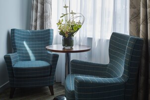 Una habitación con dos sillones tapizados y una mesita con un florero.