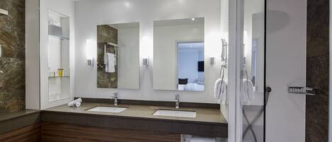 Une salle de bain moderne avec deux lavabos, une douche et des toilettes séparées par une paroi en verre.