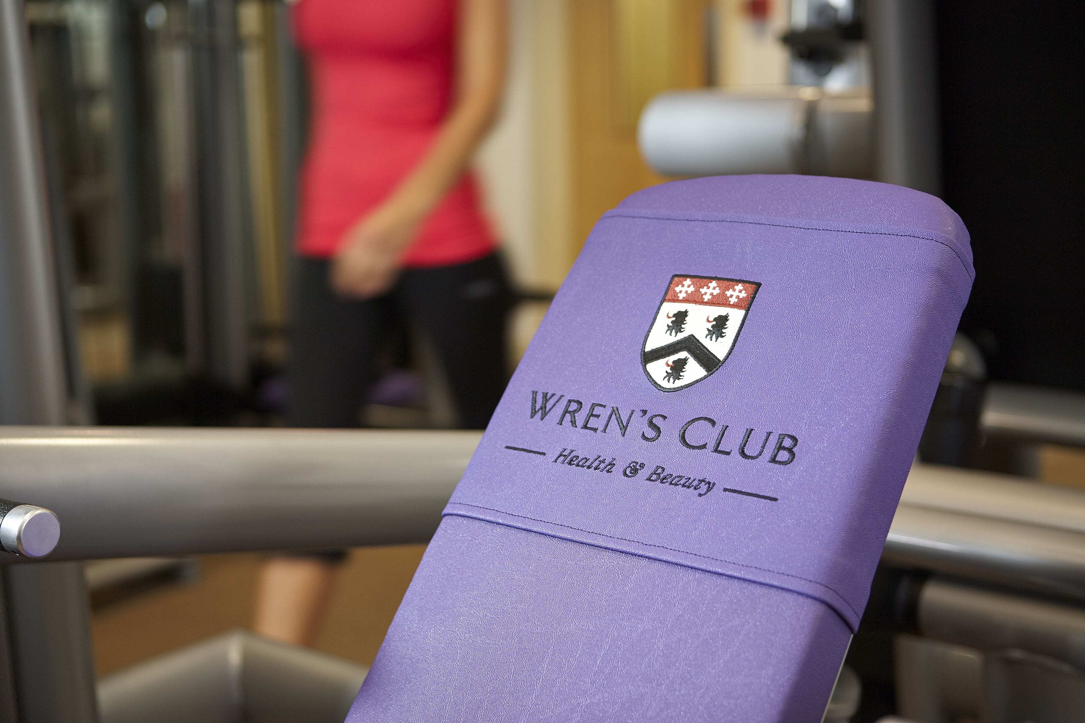 A purple gym bench with the logo "WREN'S CLUB Health & Beauty" and a shield emblem.