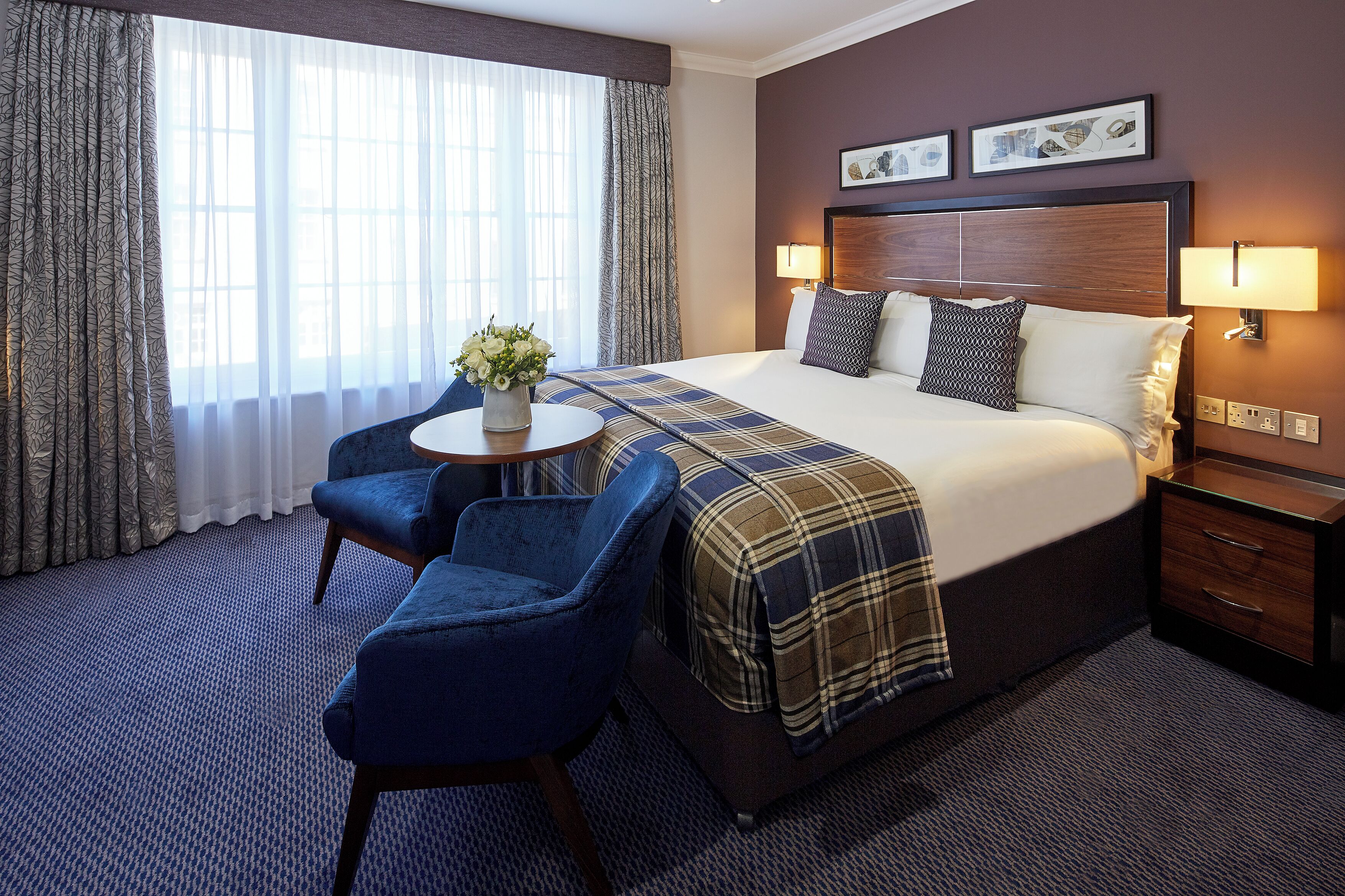 Una habitación de hotel con una cama grande, un escritorio con una silla y una ventana con cortinas.
