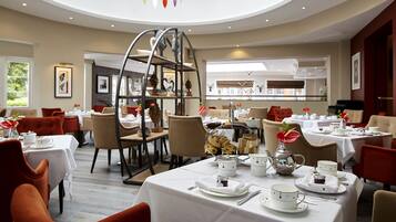 A spacious dining area with round tables, chairs, and a central decorative structure.