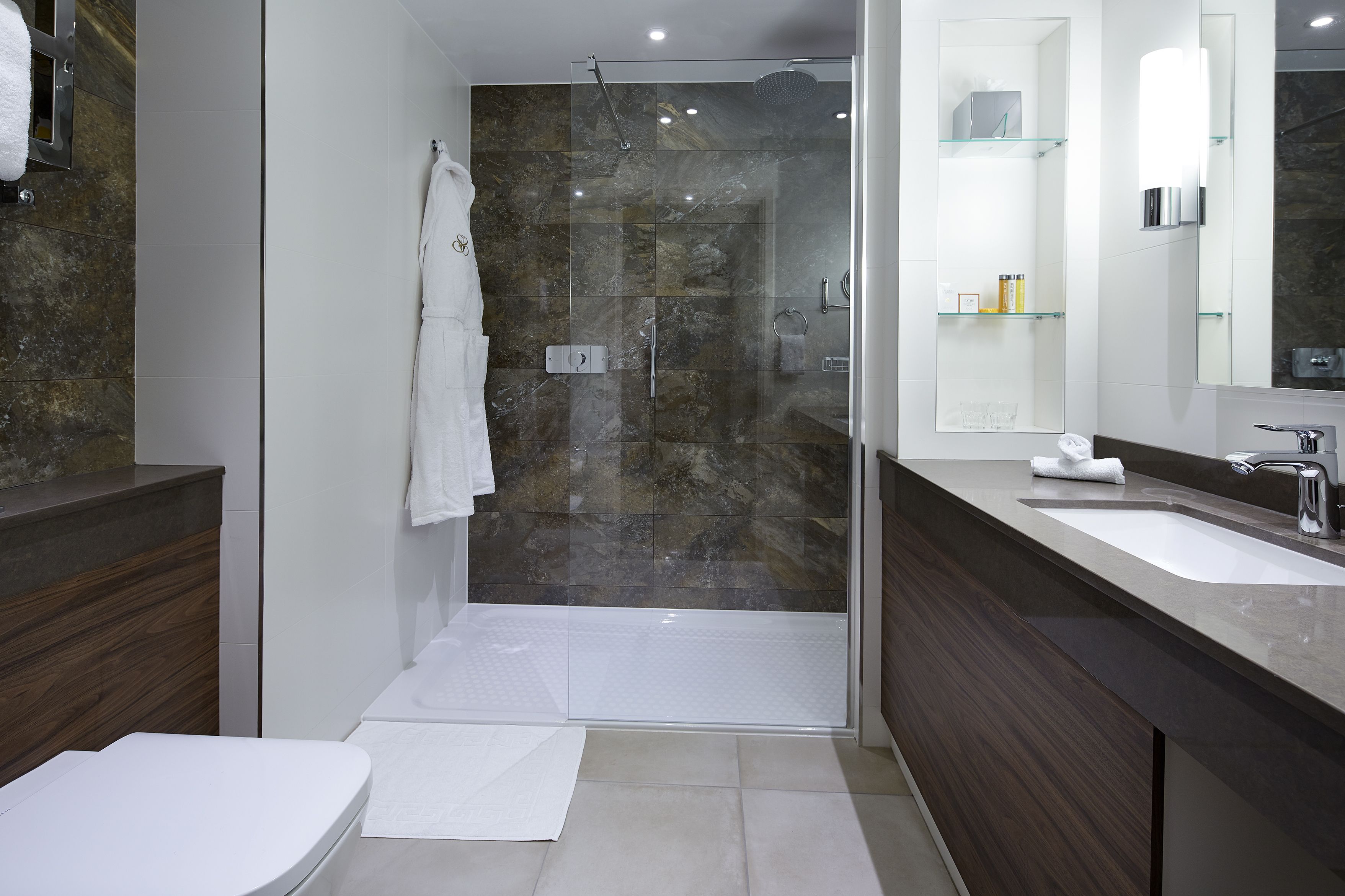 A modern bathroom with a glass-enclosed shower, a vanity with a large mirror, and a separate toilet area.