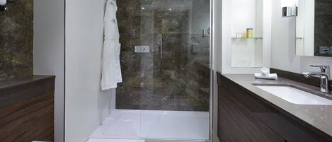 A modern bathroom with a glass-enclosed shower, a vanity with a large mirror, and a separate toilet area.