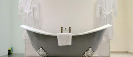 A bathroom with a freestanding bathtub, a towel hanging on the wall, and a pair of shoes on the floor.