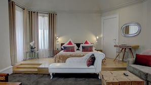 A hotel room with a bed, two white sofas, a wooden coffee table, and a small table with a vase of flowers. - Carmelite Hotel (Aberdeen)