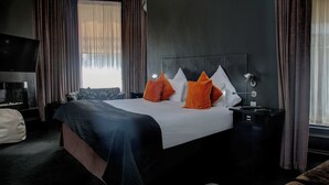 A hotel room with a large bed, a TV, and a nightstand. - Carmelite Hotel (Aberdeen)