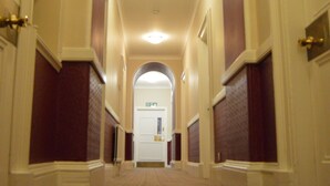 A long, narrow hallway with a carpeted floor and a series of doors on both sides. - Carmelite Hotel (Aberdeen)