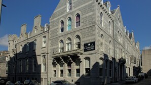 A historic building with arched windows and a sign for "Carmelite Bar & Grill" on Trinity Street. - Carmelite Hotel (Aberdeen)