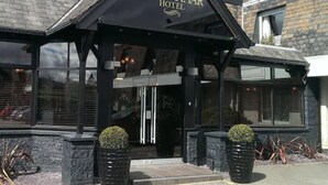 The exterior of the Craighaar Hotel with a black facade, a pitched roof, and a sign above the entrance.