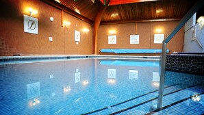 An indoor swimming pool with clear lane markings, safety signs, and wall-mounted lighting fixtures. - Fairfield House - Ayr (Ayr)