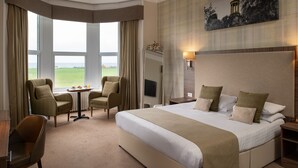 A hotel room with a large bed, two armchairs, a small table with a tray of breakfast items, a large window with curtains, and a painting on the wall. - Fairfield House - Ayr (Ayr)