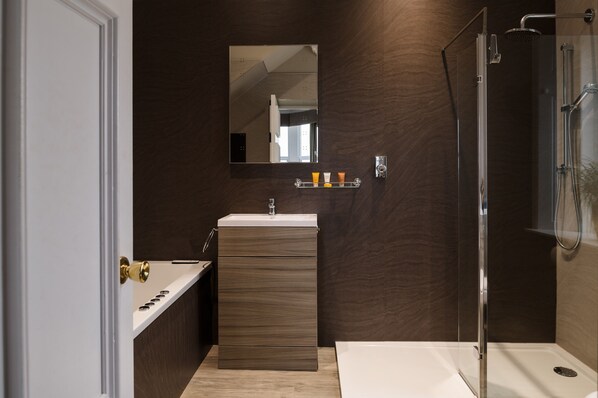 A modern bathroom with a bathtub, a vanity with a mirror, and a shower enclosure.