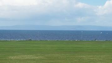 Een grasveld met uitzicht op de zee en verre bergen.