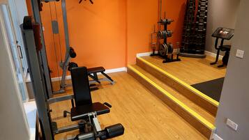 A gym with weightlifting equipment, a bench, and a step platform.