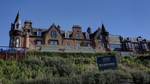Un hotel histórico con múltiples torres y almenas, llamado 'Braid Hills Hotel'.
