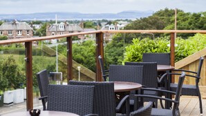 Una terraza con mobiliario de mimbre y vistas a casas y vegetación.