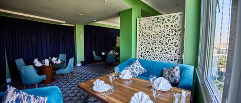Un comedor con una mesa de madera dispuesta para cuatro personas, asientos tapizados en azul y un panel decorativo blanco.