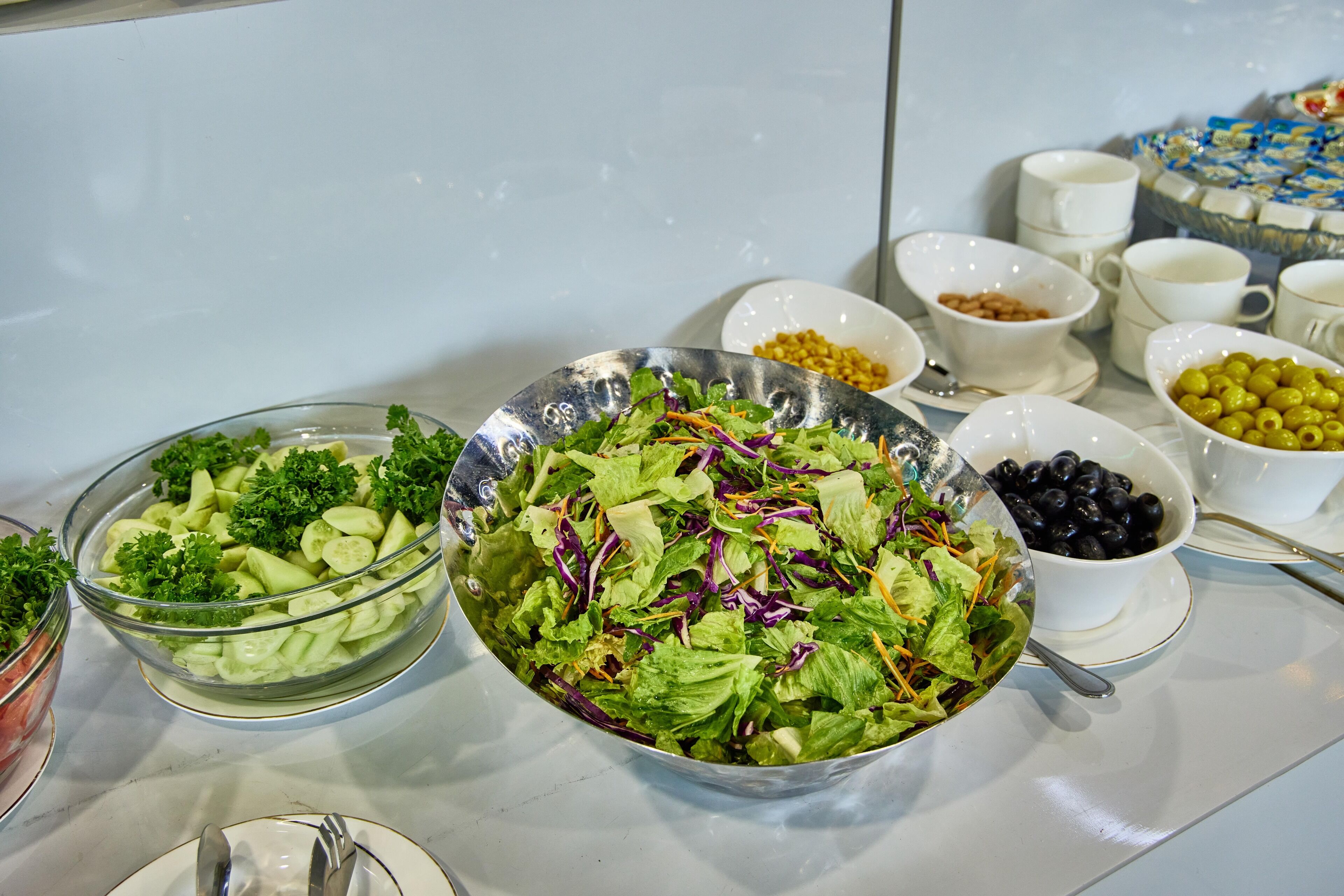 A buffet table with various dishes including salads, olives, and other food items.