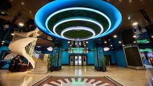 Hotellin aula, jossa on keskeisellä paikalla sijaitseva spiraalimainen portaikko, vastaanottotiski ja kyltti, jossa lukee: ”Hotel Uzbechka”.