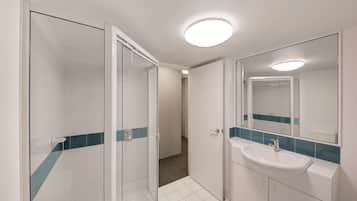 A modern bathroom with a glass shower enclosure, a white sink with a blue tile backsplash, and a large mirror.