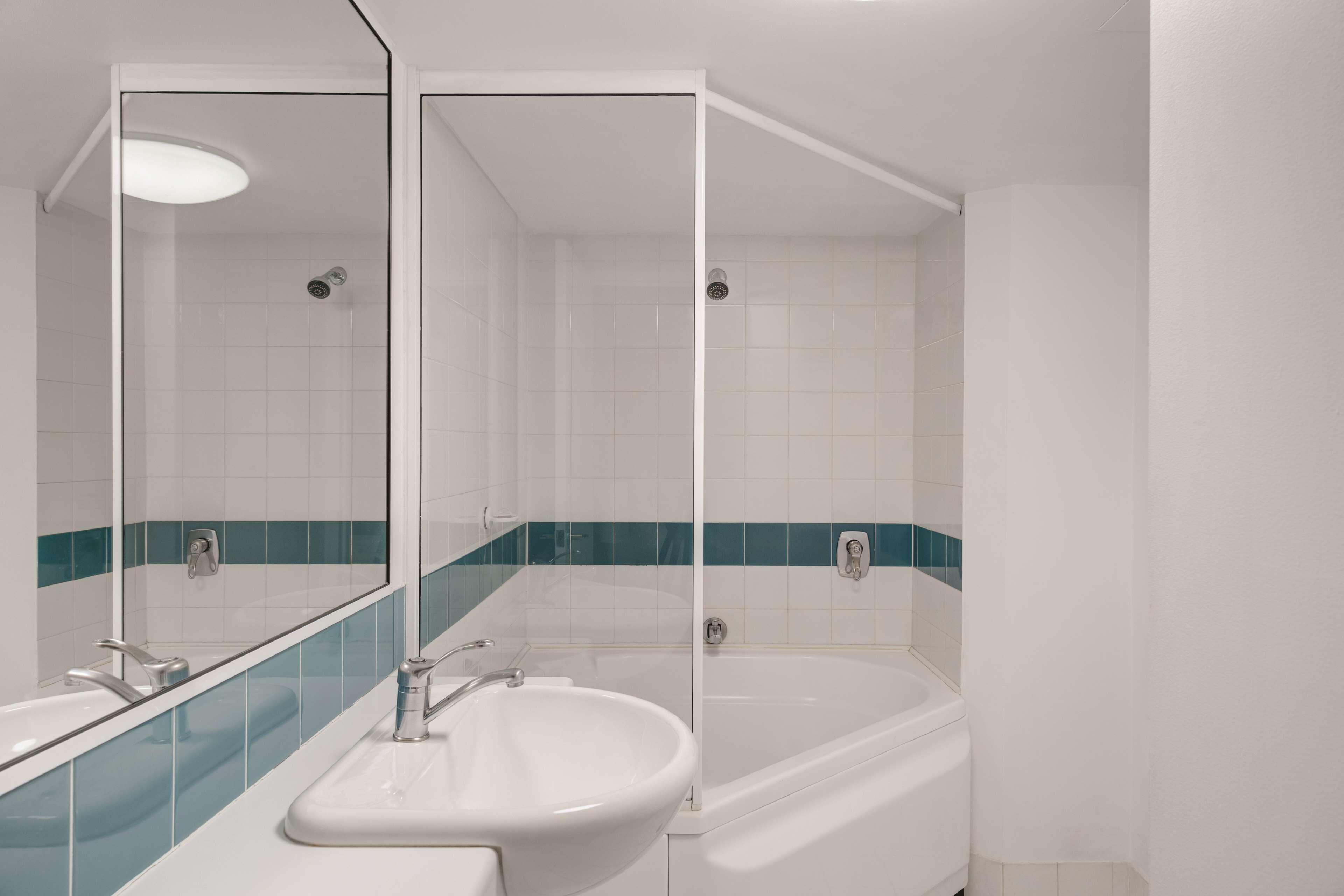 A bathroom with a white sink, a bathtub, and a mirror.