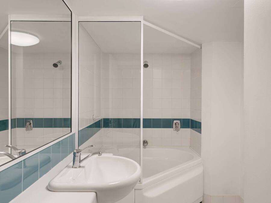 Un baño con un lavamanos blanco, una bañera y un espejo.
