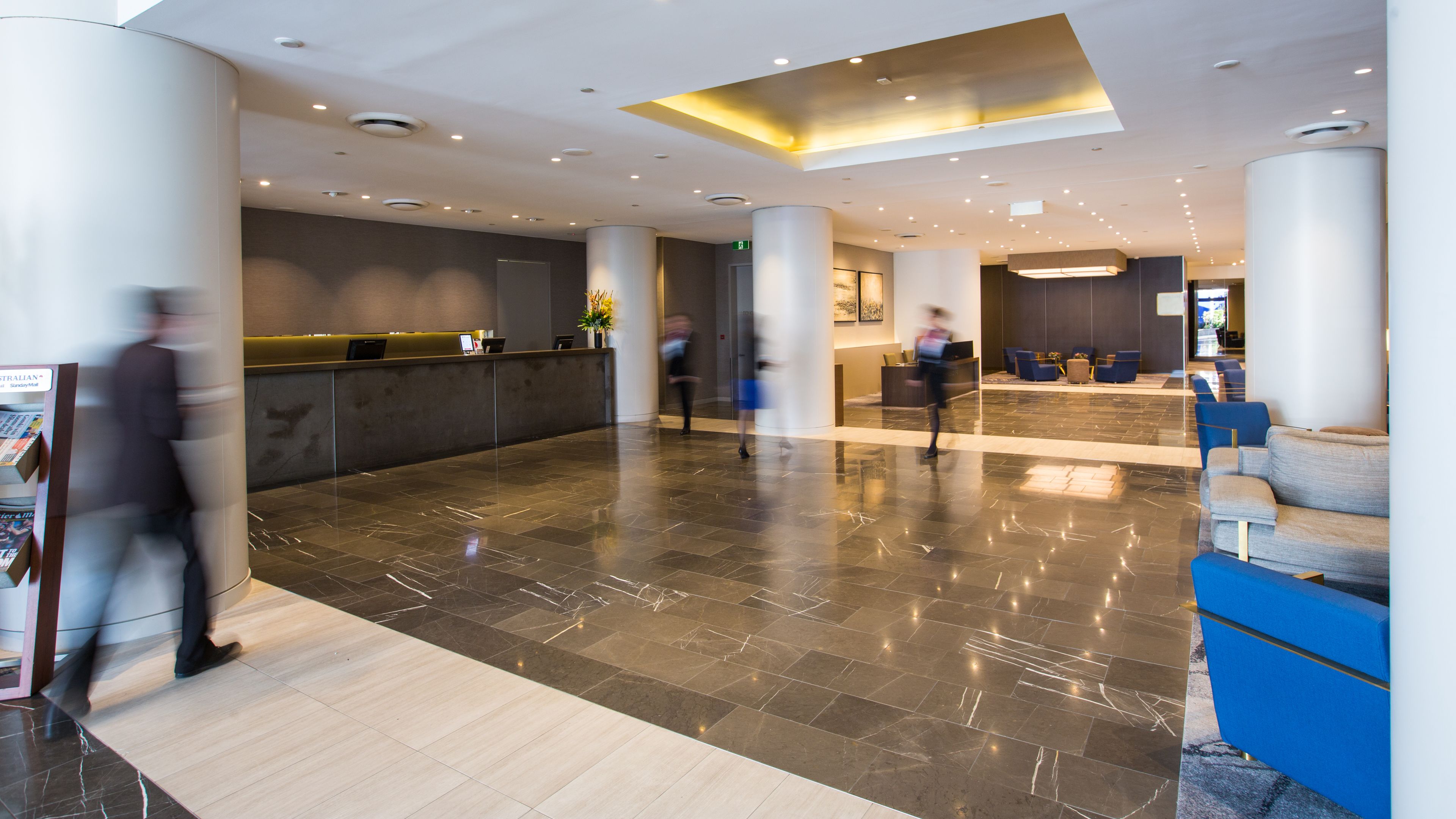 A modern lobby with marble flooring, a reception desk, and seating areas.