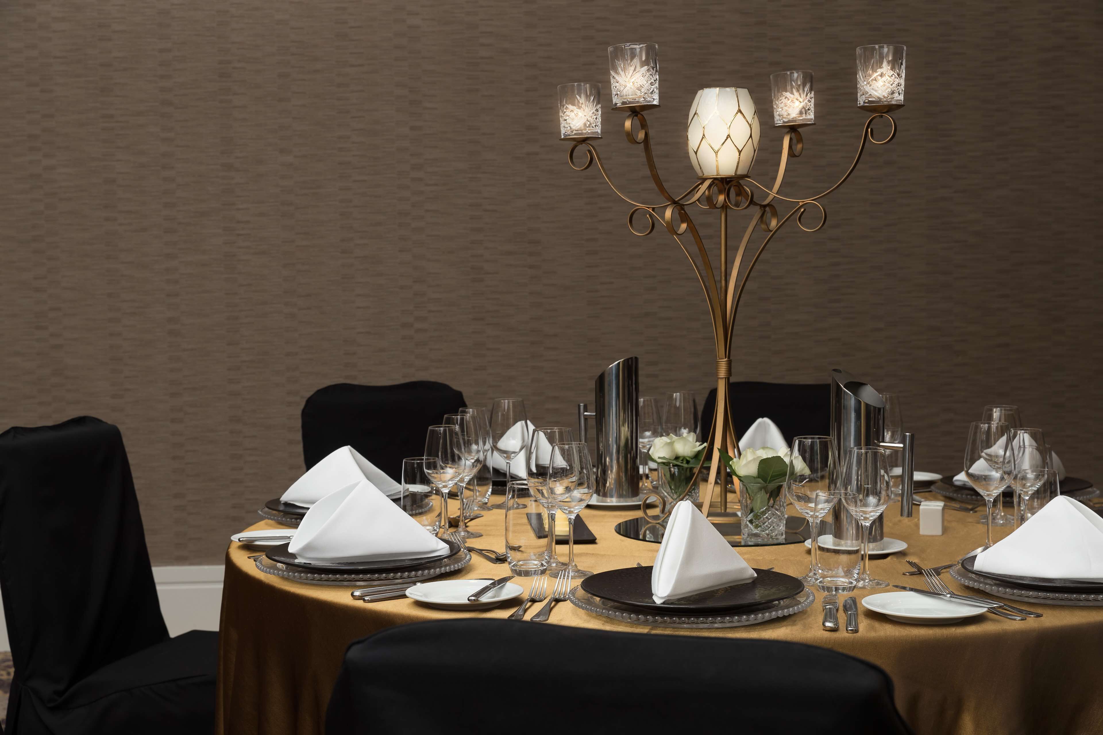 Una mesa de comedor preparada con varios puestos individuales, incluyendo platos, vasos y cubiertos.