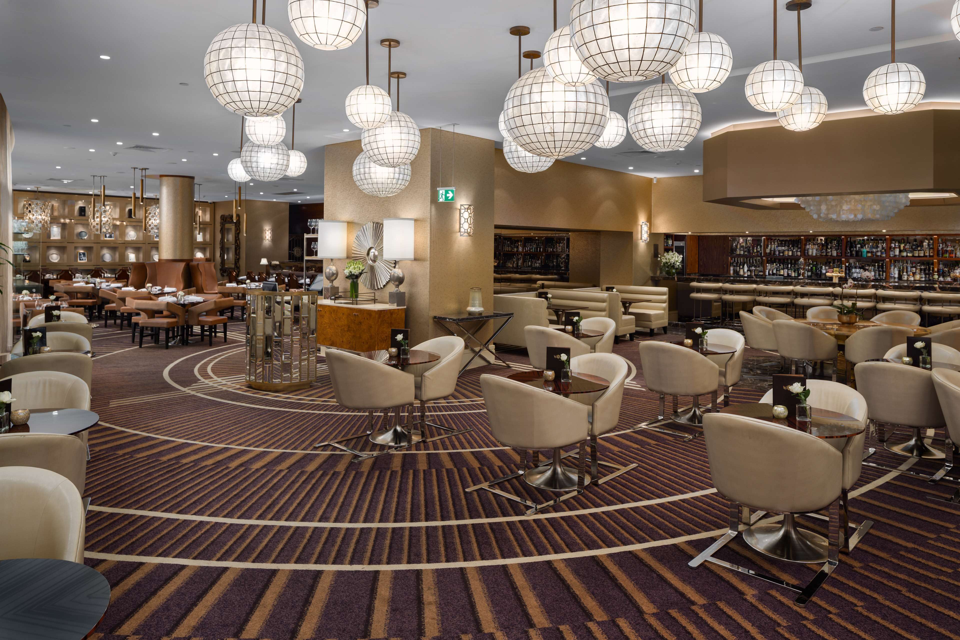 A hotel lobby with multiple seating areas, a bar, and a reception desk.