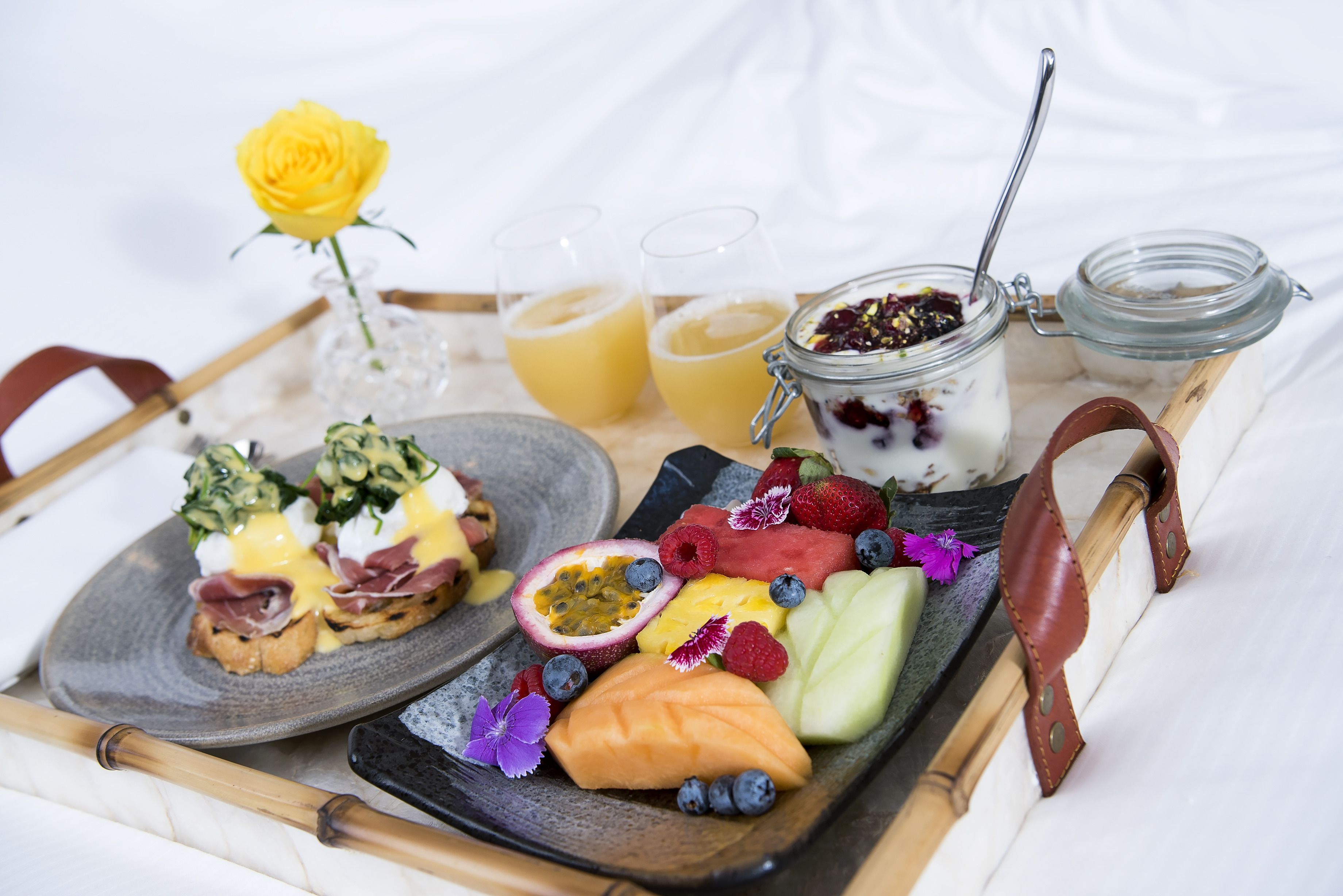 A breakfast tray with a variety of foods including eggs, fruits, and a drink.