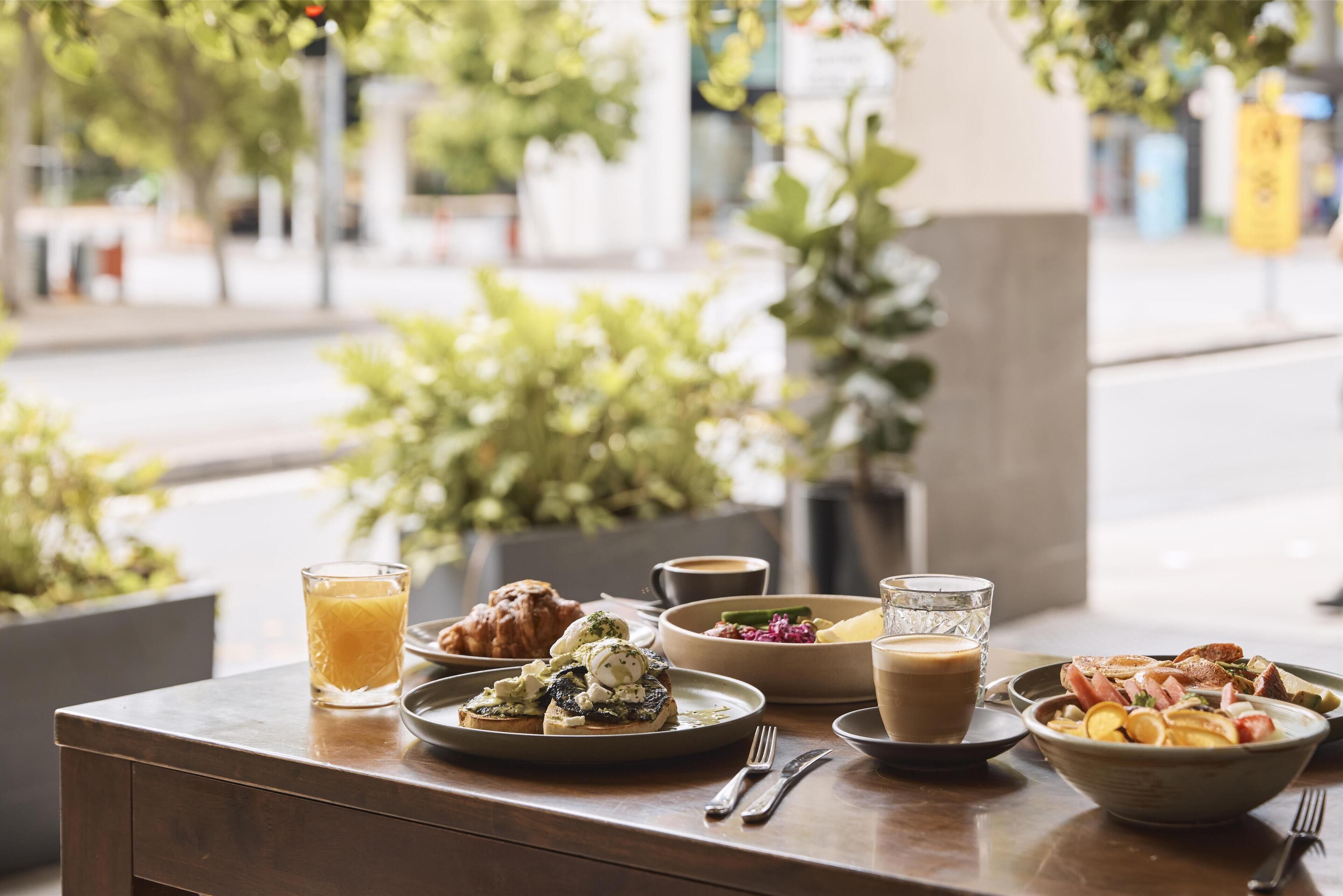 A breakfast table with various dishes, including eggs, pastries, and a bowl of fruit.