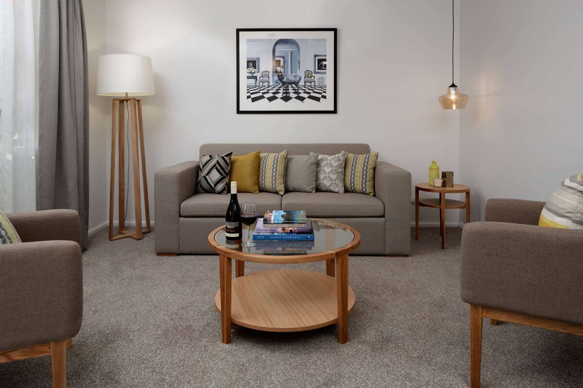 A living room with a sofa, a coffee table, a floor lamp, and a framed picture on the wall.