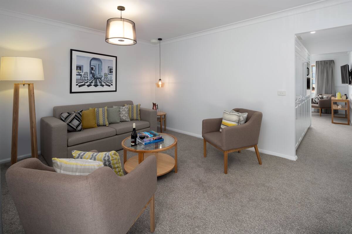 A modern living room with a sofa, armchairs, a coffee table, and a painting on the wall.