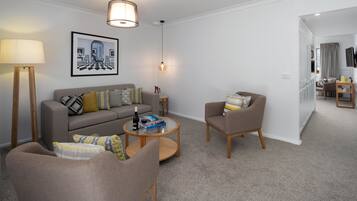 A modern living room with a sofa, armchairs, a coffee table, and a painting on the wall.