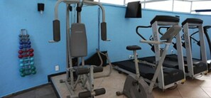 Une salle de sport équipée de matériel d’exercice, notamment une machine de musculation, des tapis de course et des haltères.