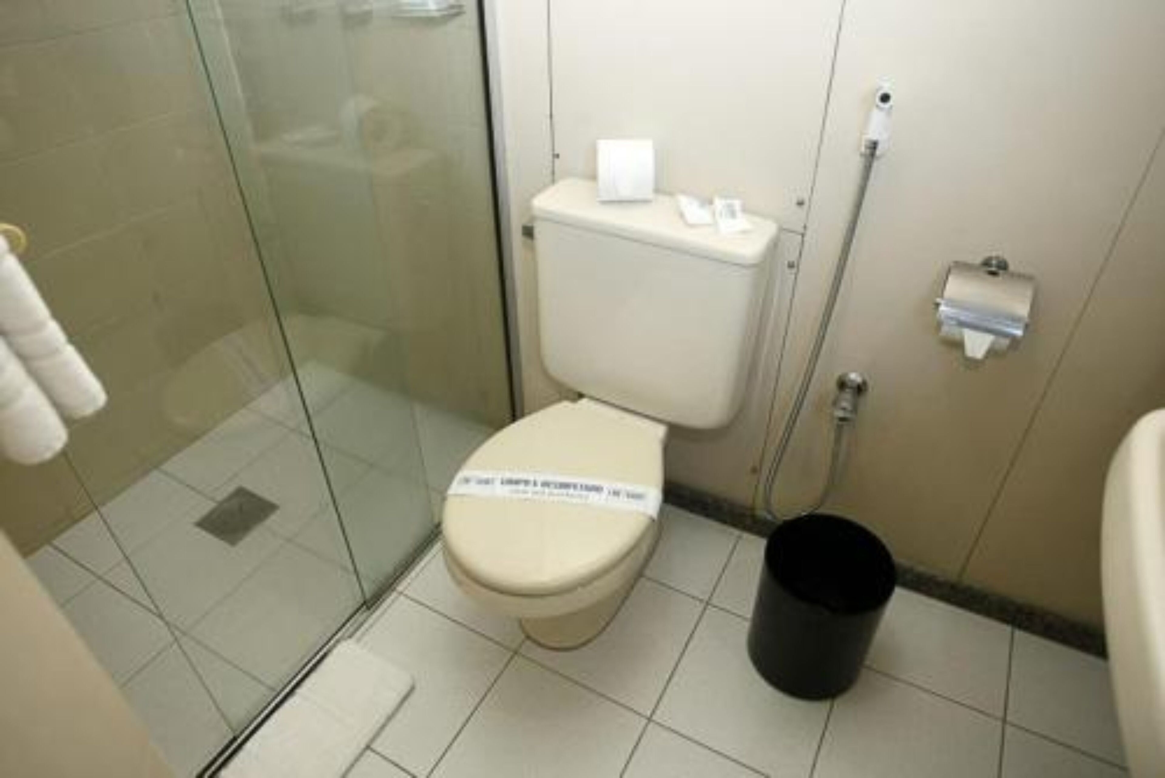 Une petite salle de bain comprenant des toilettes, une douche à parois de verre et une poubelle.