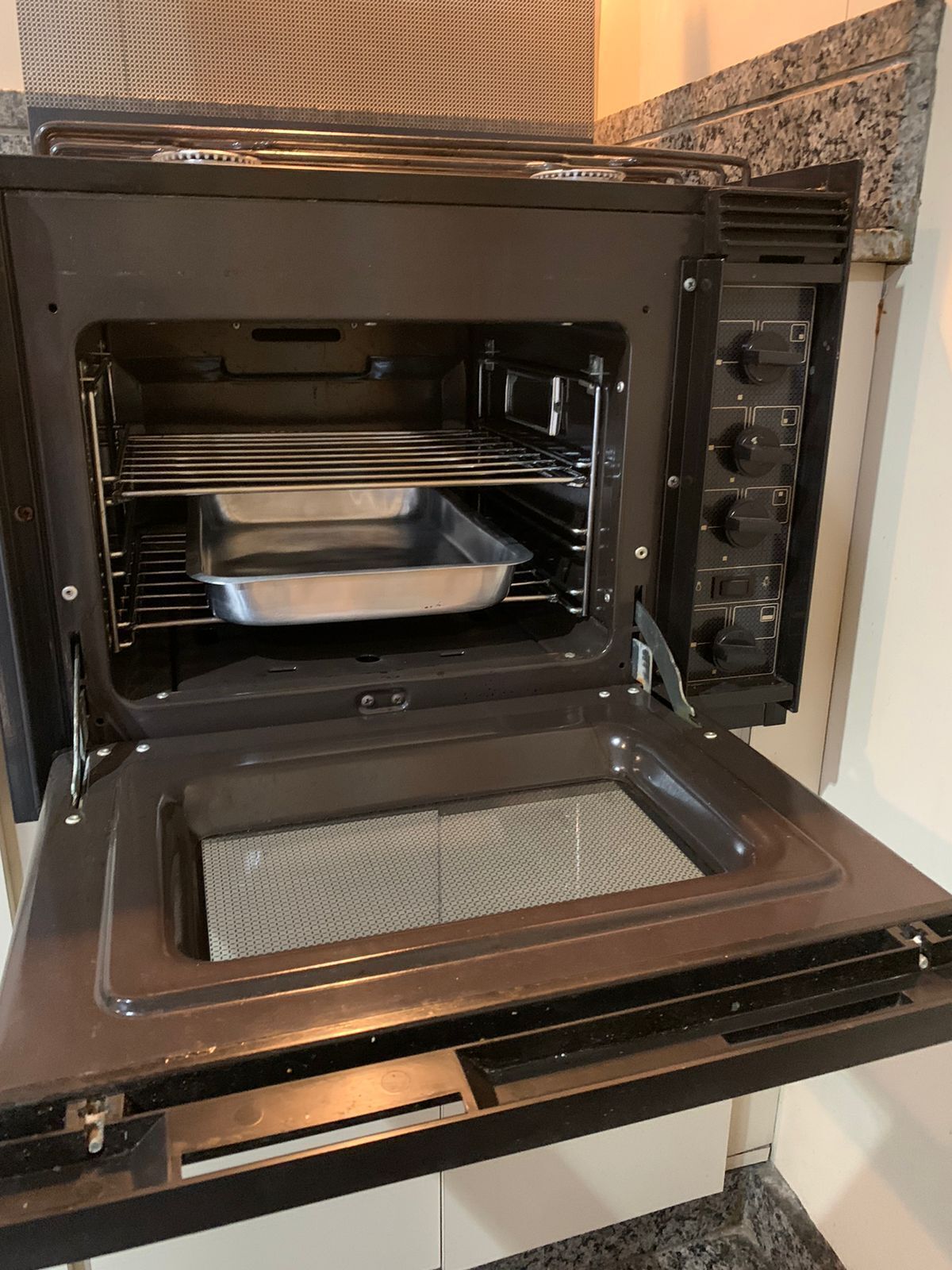 Horno eléctrico abierto con una bandeja metálica en su interior.