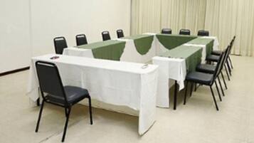 A conference room with a long table and chairs, white tablecloths, and a green runner.