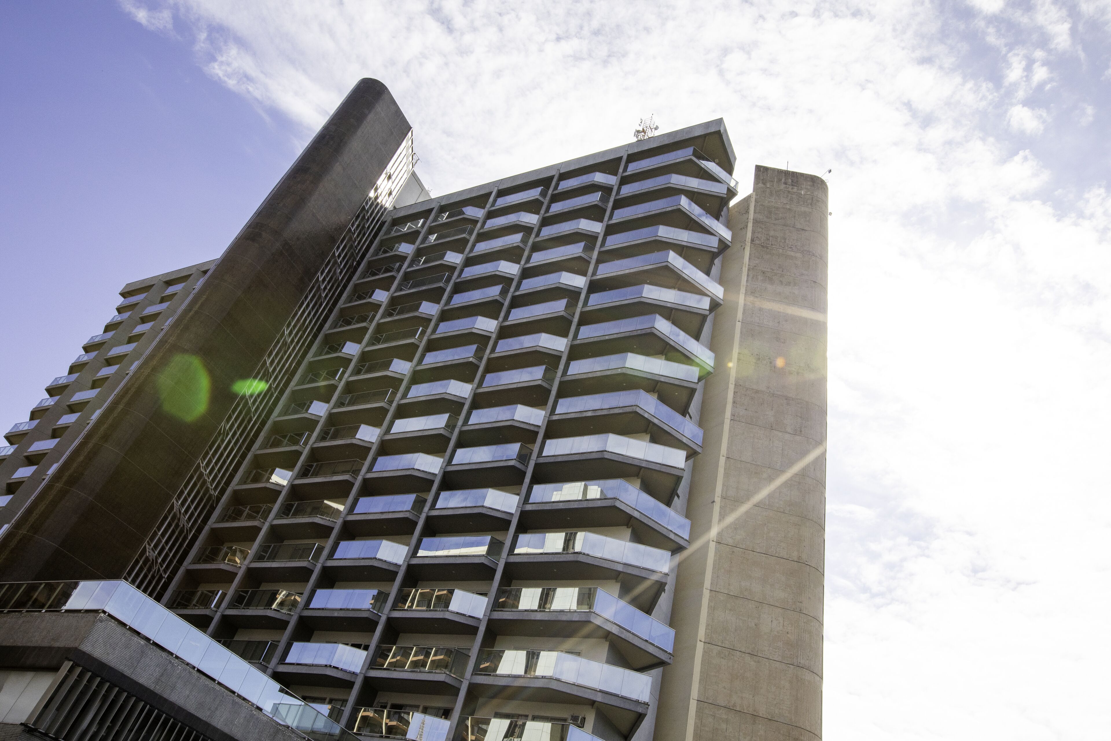 Um edifício alto com várias varandas e design arquitetônico moderno.