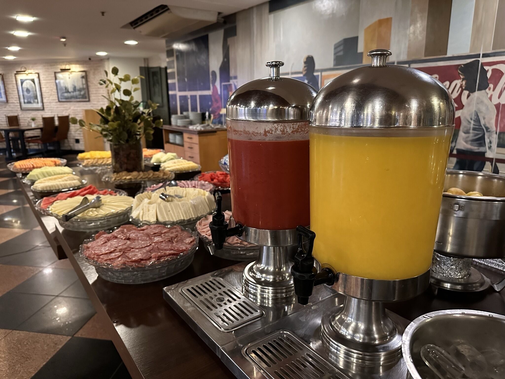 Buffet com diversos alimentos e dois distribuidores de bebidas.